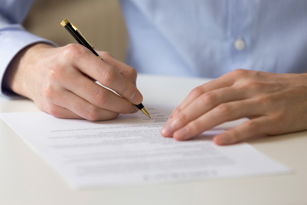 Hands with a pen signing a document