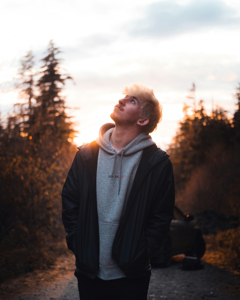 man black jacket standing near trees