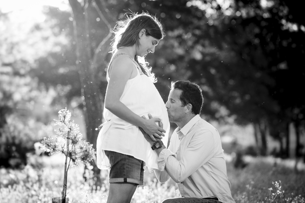 man kissing pregnant belly of his wife