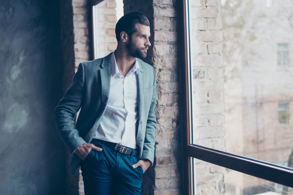 man looking out a window with his hands in his pockets