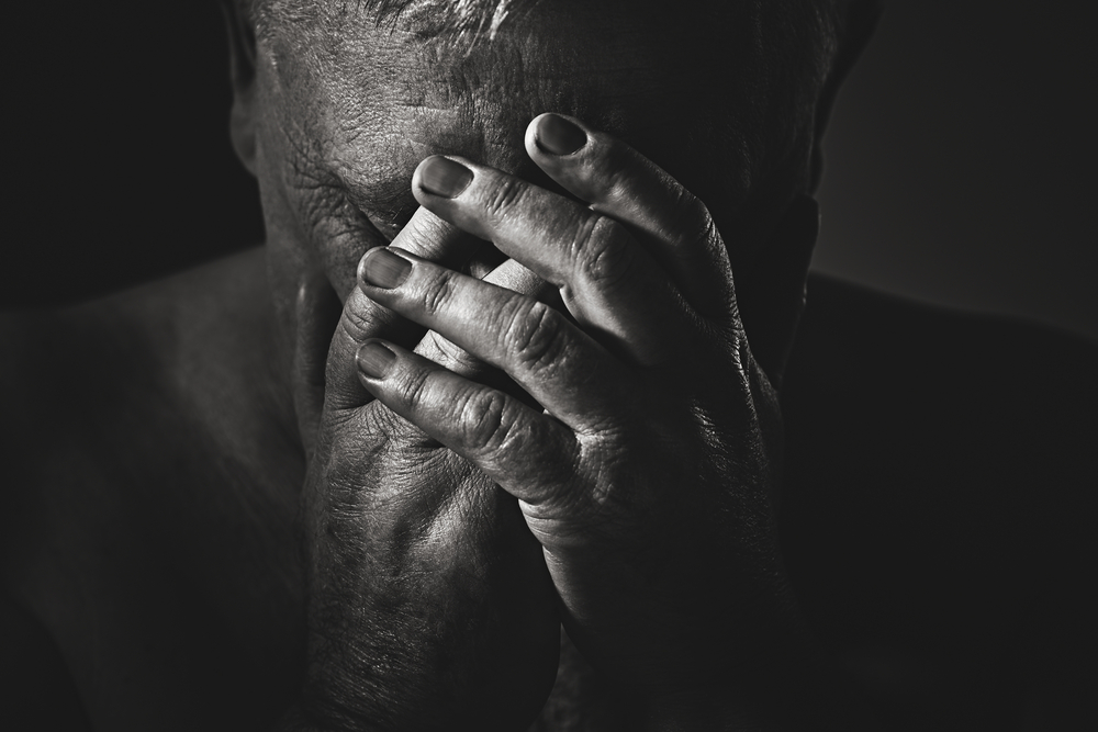 older man with hands over his face BW