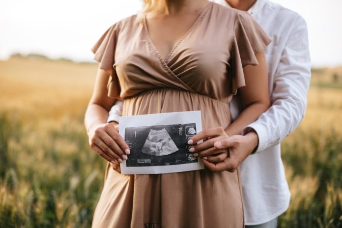 Pregnant woman with husband holding ultrasound