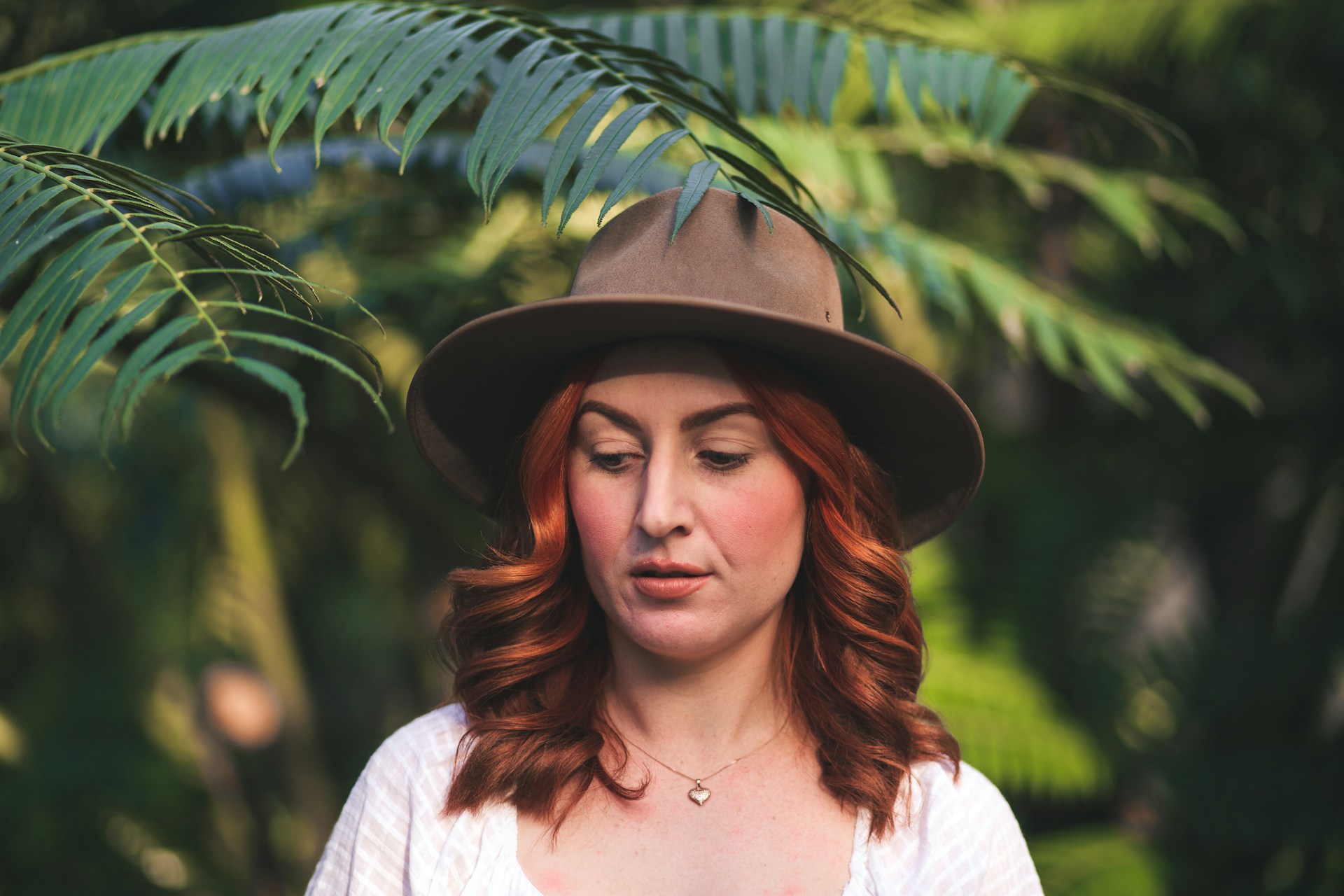 woman in a hat near leafy trees