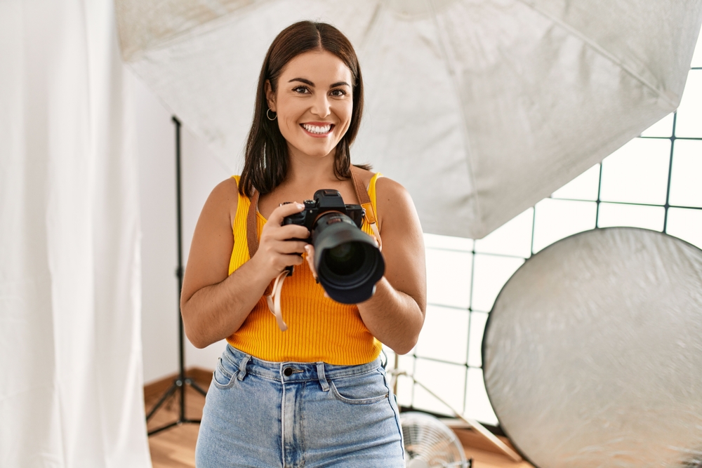 woman photographer holding professional camera in her photo studio